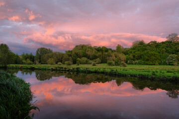 Pink skies as the sun sets over the River Wey and meadows in Godalming, Surrey, UK