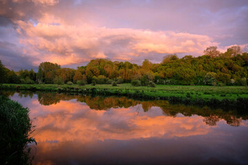 Fototapeta na wymiar Pink skies as the sun sets over the River Wey and meadows in Godalming, Surrey, UK