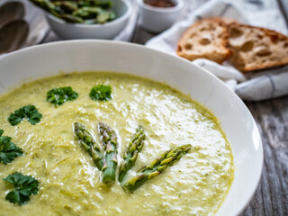 Cream asparagus soup on wooden table
