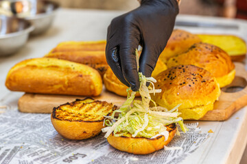 Chef prepares fresh delicious burger with ingredients. Closeup. Fast food