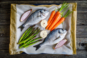 Fresh dorada and vegetables on wooden background
