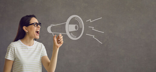 Serious woman draws attention to an important event by shouting loudly into a loudspeaker. Woman...