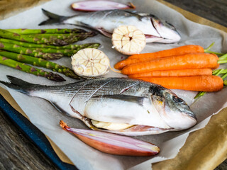 Fresh dorada and vegetables on wooden background

