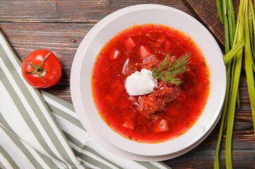 borscht with sour cream and herbs on a wooden