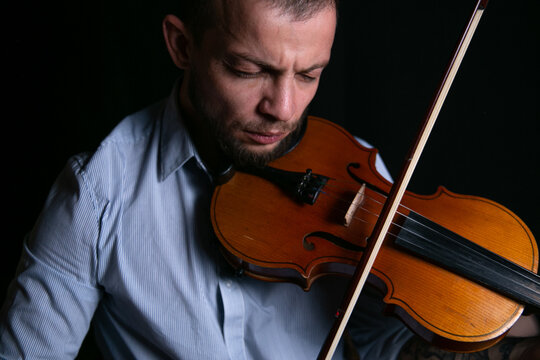 male violinist on a black background plays music on the violin