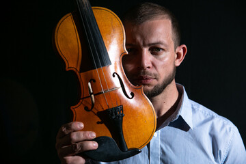 portrait of a man with a violin in his hands on a black background