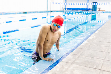 young disabled latin man swimmer leaning on poolside in Mexico in disability concept