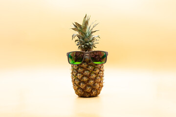 Funny pineapple with sunglasses over pastel yellow background