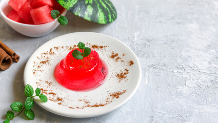 Gelo di melone, pudding, jelly with mint and cinnamon on a white plate on a light background....