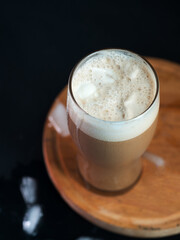 A glass of iced coffee with ice cream on the dark table