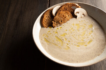 cream soup of champignons on a wooden table with bread chips close-up