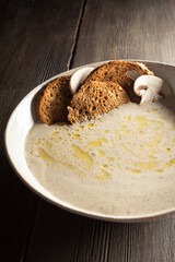 cream soup of champignons on a wooden table with bread chips close-up