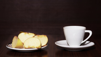 White coffee cup and plate with apples on dark background