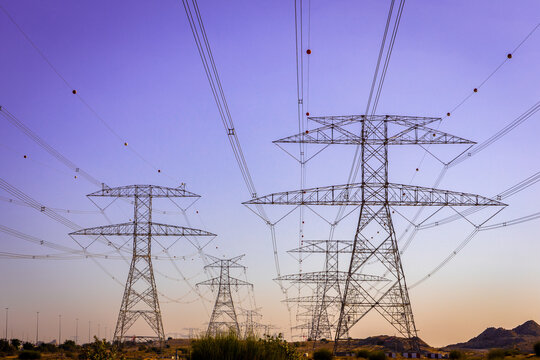 High voltage eletrical towers and lines, symmetrical view with purple sky in the background, Dubai, United Arab Emirates.