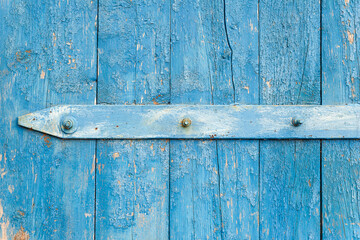 Wooden background. Old blue shabby wooden door with iron fasteners. Torn up dilapidated boards. Natural creative texture for editing and design.