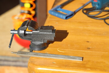 Small locksmith vise and file on a wooden work table in the country, tools of the master