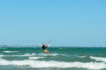 Kerch, Russia - 18 August 2020: Kite surfing on the blue sea in the background of blue sky at summer time. Kiteboarding. Fun in the ocean. Extreme Sport , surfing man