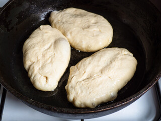 stuffed pies are frying in oil in pan at home