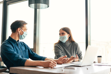 working group in protective masks discussing financial data.