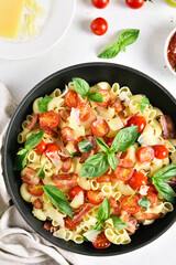 Tomato and bacon pasta with parmesan cheese and basil leaves