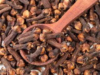 top view of spoon on pile of dried cloves closeup