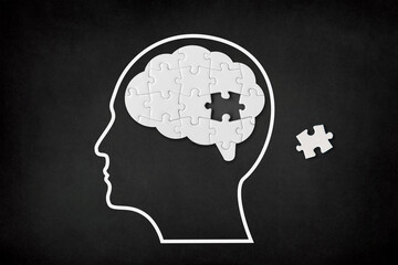 Brain shaped white jigsaw puzzle on black background, a missing piece of the brain puzzle, mental health and problems with memory