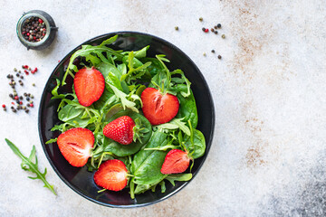 strawberry salad green leaves salad mix arugula, spinach organic on the table healthy food meal snack copy space food background rustic. top view keto or paleo diet veggie vegan or vegetarian food