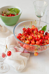 Red cherries into a bowl, white background