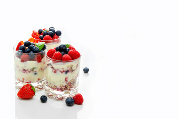Muesli with yogurt and berries in a glass On a white background. Dessert preparation process. Fitness food. Copy space.