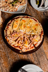 Delicious Crunchy Artisan Pizza with melted cheese on a round plate over a wooden table