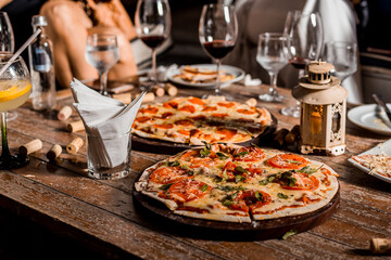Delicious Crunchy Artisan Pizza with melted cheese on a round plate over a wooden table