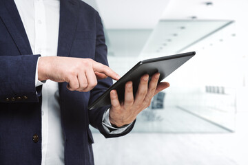 Man using digital tablet in bright sunny office, close up. Technology concept
