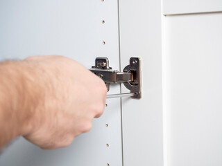 close-up installation of furniture doors with a screwdriver, the concept of furniture assembly. Selective Focus