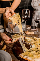 Female Hands Grabs a beautiful Pizza Slice with melted cheese on a wooden table