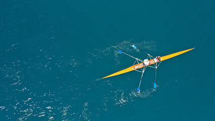 Aerial drone top down view of sport canoe operated by team of young trained athletes in deep blue...