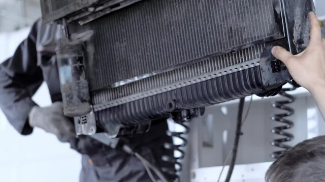 A professional mechanic installs a fan radiator on a truck during an annual maintenance service at a truck service station