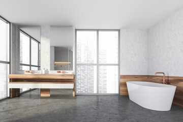 Fototapeta na wymiar Modern design bathroom interior with white oval bathtub, double sink countertop, bronze faucets. Panoramic window with skyscrapers city view. Wood and concrete materials.