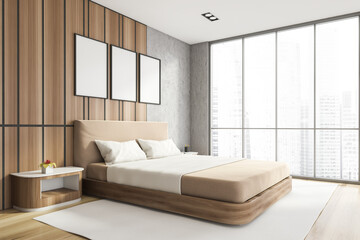 Modern stylish bedroom interior with wooden walls, parquet floor, master bed and Panoramic window. Three White framed posters on the wall. Mockup concept.