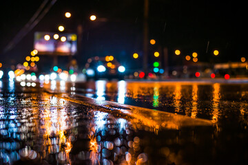 Obraz premium Rainy night in the big city, the light from the headlamps of approaching car on the highway. View from the level of the dividing line