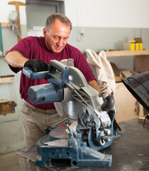 Confident workman cutting wooden planks using circular saw. High quality photo