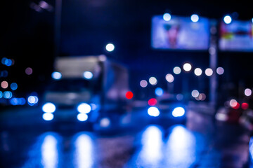 Fototapeta na wymiar Rainy night in the big city, cars traveling on wet highway. Defocused image