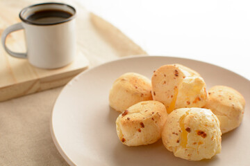 Minas Gerais cheese bread, hot, with a cup of black coffee and butter, on a checkered picnic tablecloth