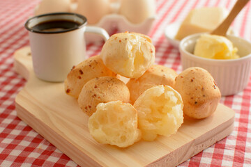 Minas Gerais cheese bread, hot, with a cup of black coffee and butter, on a checkered picnic...