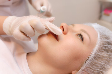 Fototapeta na wymiar The cosmetologist prepares the client's lips for the augmentation procedure