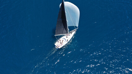 Aerial drone top down photo of beautiful sail boat with trained crew cruising in deep blue Aegean...