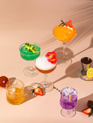 Summer cocktails with fruit and ice on pink table in sunlight with a palm tree shade