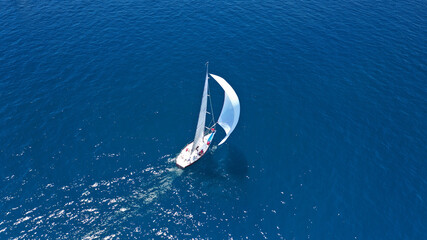 Aerial drone top down photo of beautiful sail boat with trained crew cruising in deep blue Aegean...