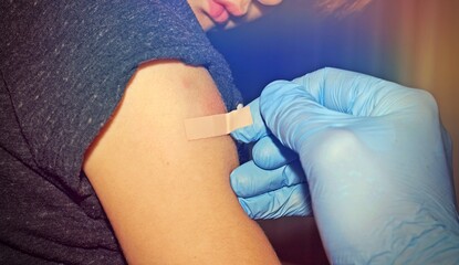 Close up of a kid arm after vaccination. Doctor is placing a bandage after the needle pain.