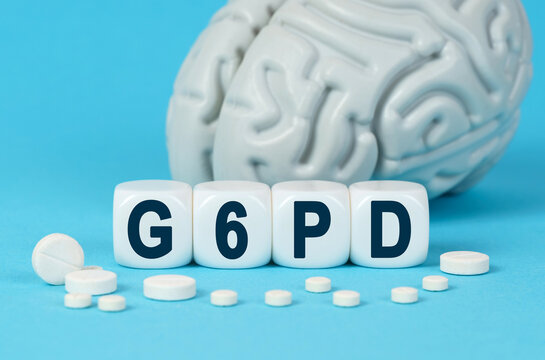 Cubes lie on the table among the pills and imitation of the brain. The text on the dice - G6PD