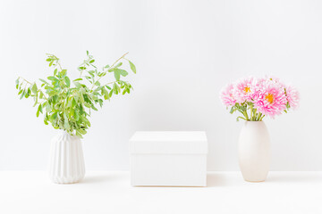 Empty white box and pink flowers in a vase on a light background. Mockup banner, podium for display of advertise product